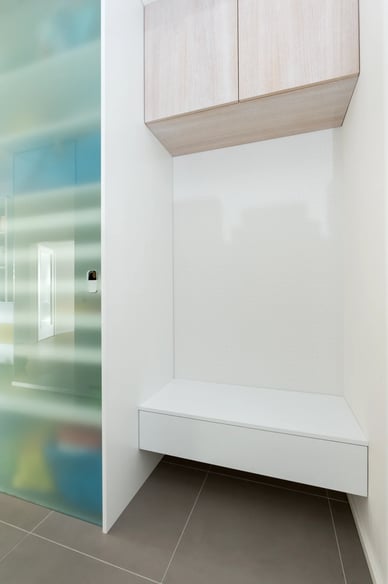 Minimalistický interiér s bílým nábytkem a šedou dlažbou.